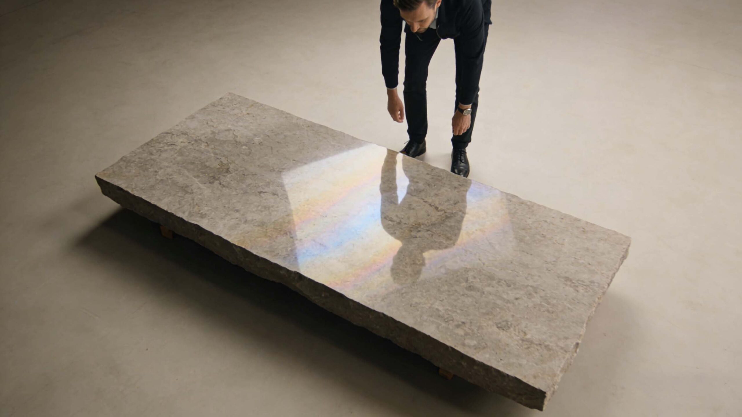 Professional buyers using angled light to detect slab cracks and resin repairs during stone quality inspection at a trade fair